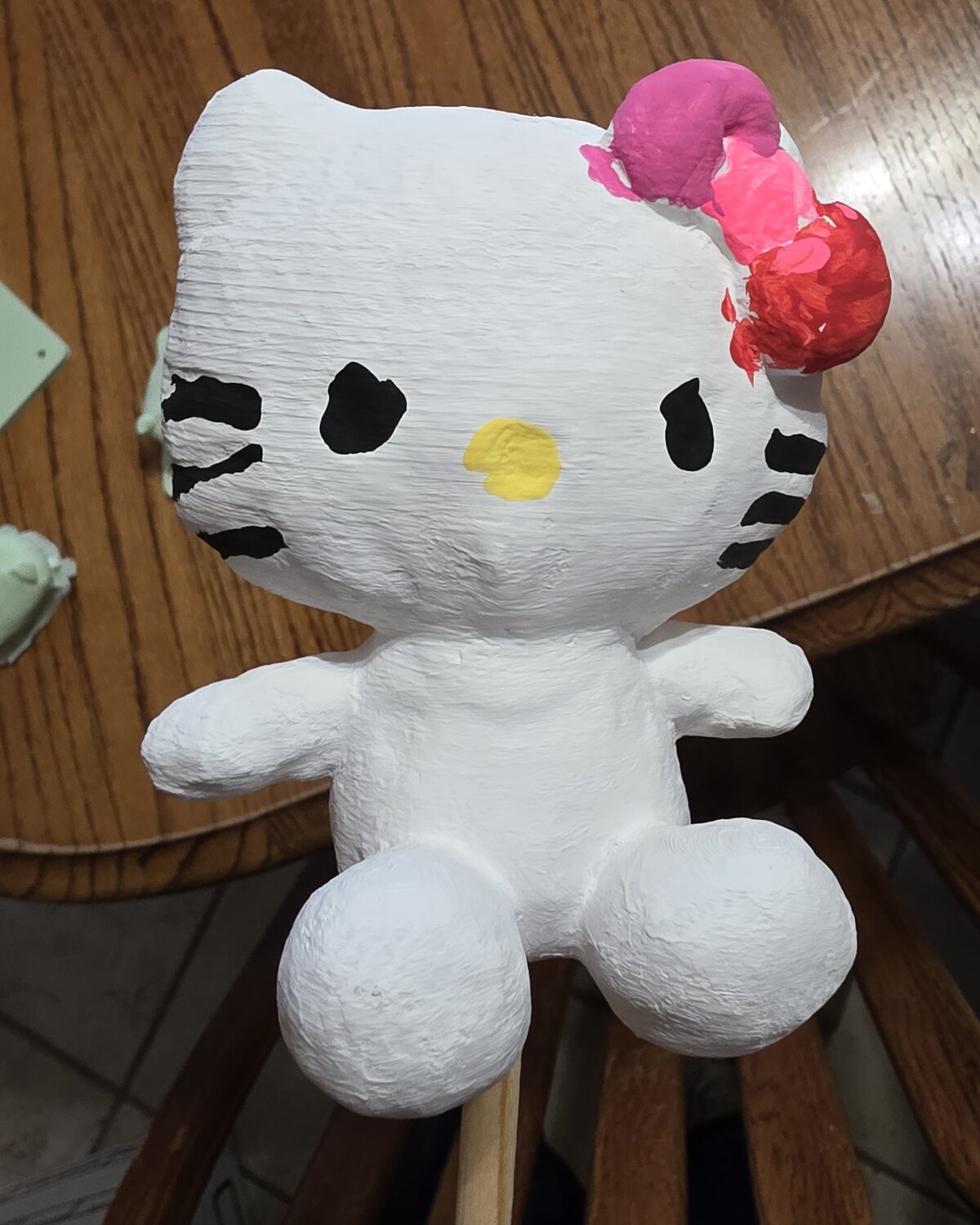 A primed white cat mini on the table, bow half-painted, seen from above