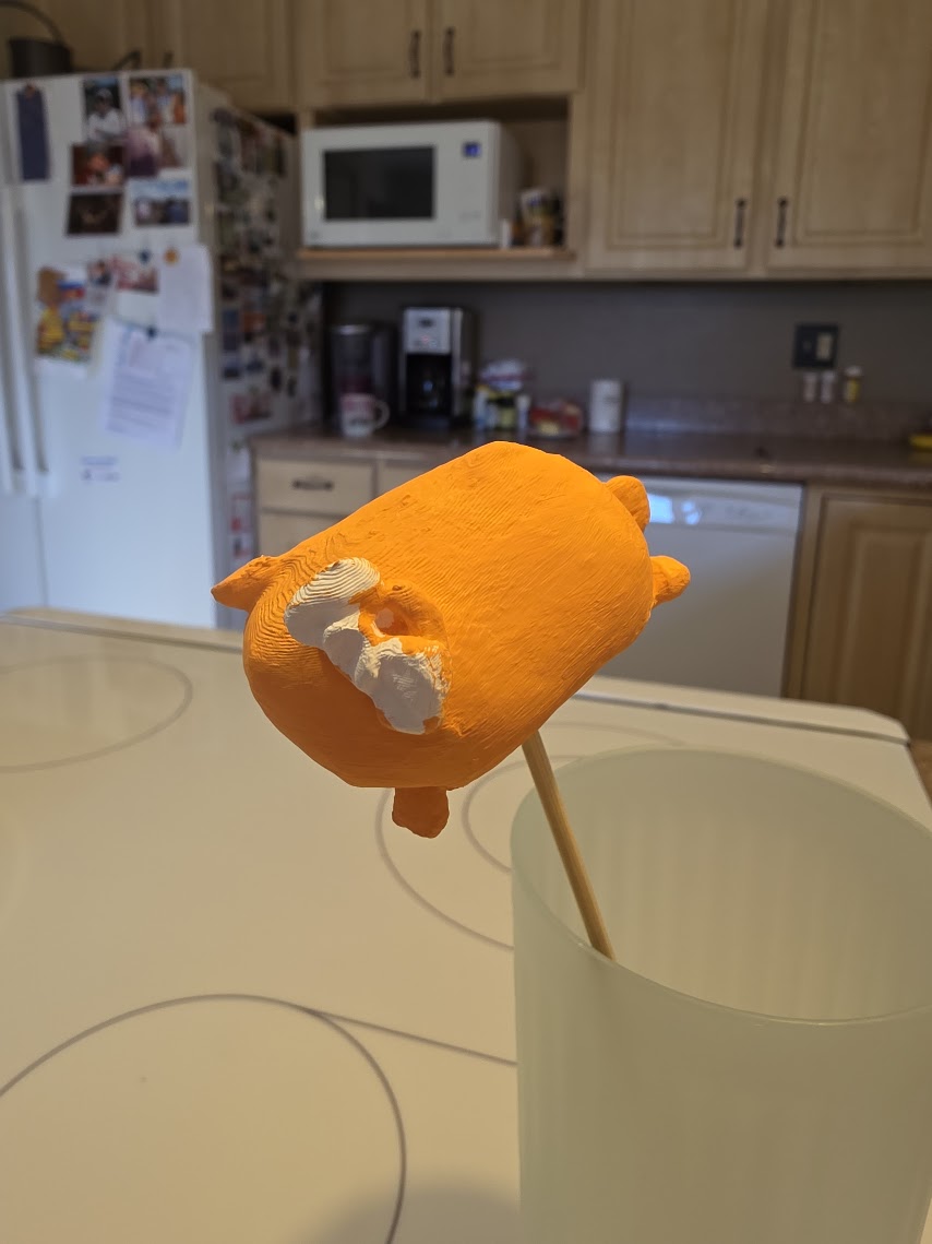A mini drying on a stick after its first orange coat