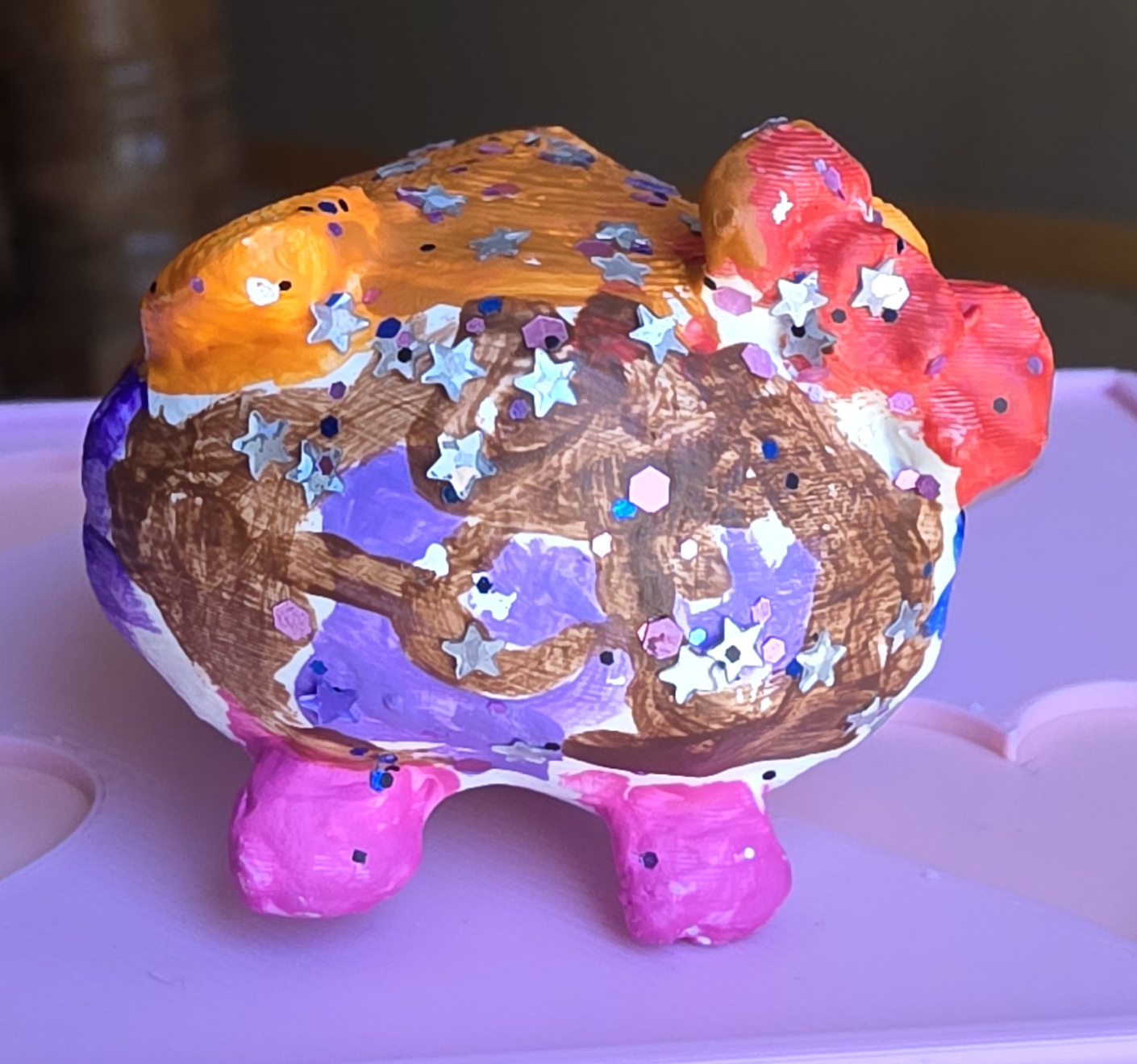 The finished rainbow-painted Loaf Kitty mini — the little friend she's bringing to life in the photo